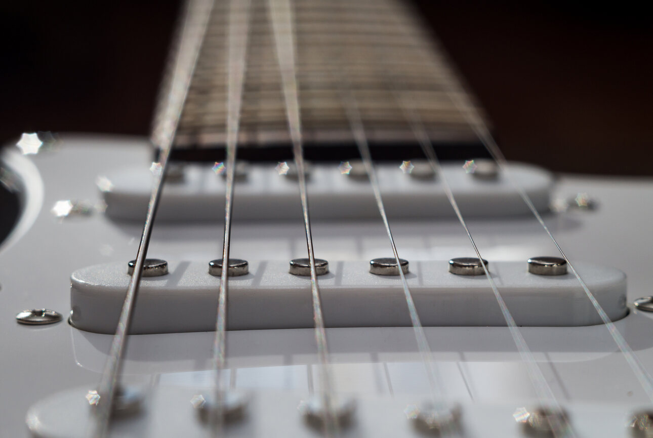 Closeup of the strings over single coils of a Fender Stratocaster electric guitar.