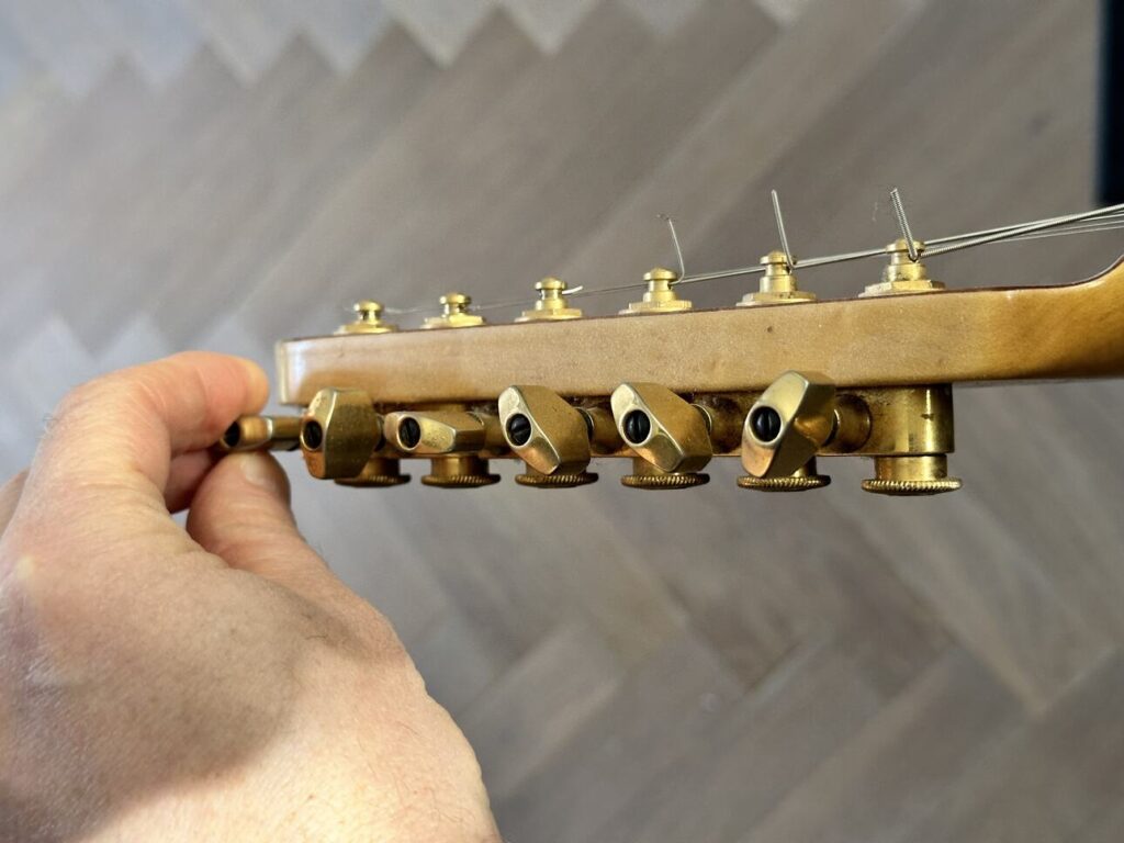 Closeup of a hand tuning-the high e-string on an electric guitar.
