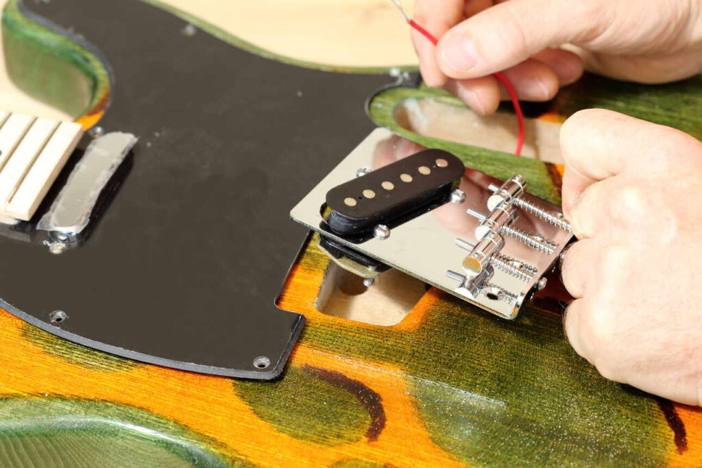 Someone soldering a slanted single coil bridge pickup on a Telecaster.