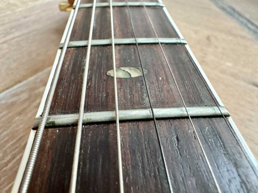 Closeup of an Ibanez s540 electric guitar neck with traces of green verdigris on the frets.
