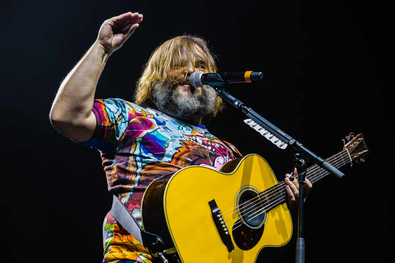Jack Black of Tenacious D wearing an acoustic guitar during a live performance in the Amsterdam Ziggo Dome.