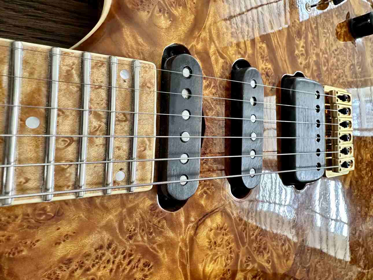 Closeup of a Lindy Fralin single coils and humbucker pickup set on a burl maple top.