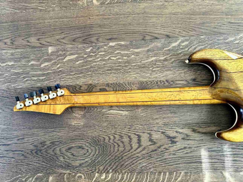 Closeup of the backside of a glued-on birdseyemaple neck on a custom built electric guitar.