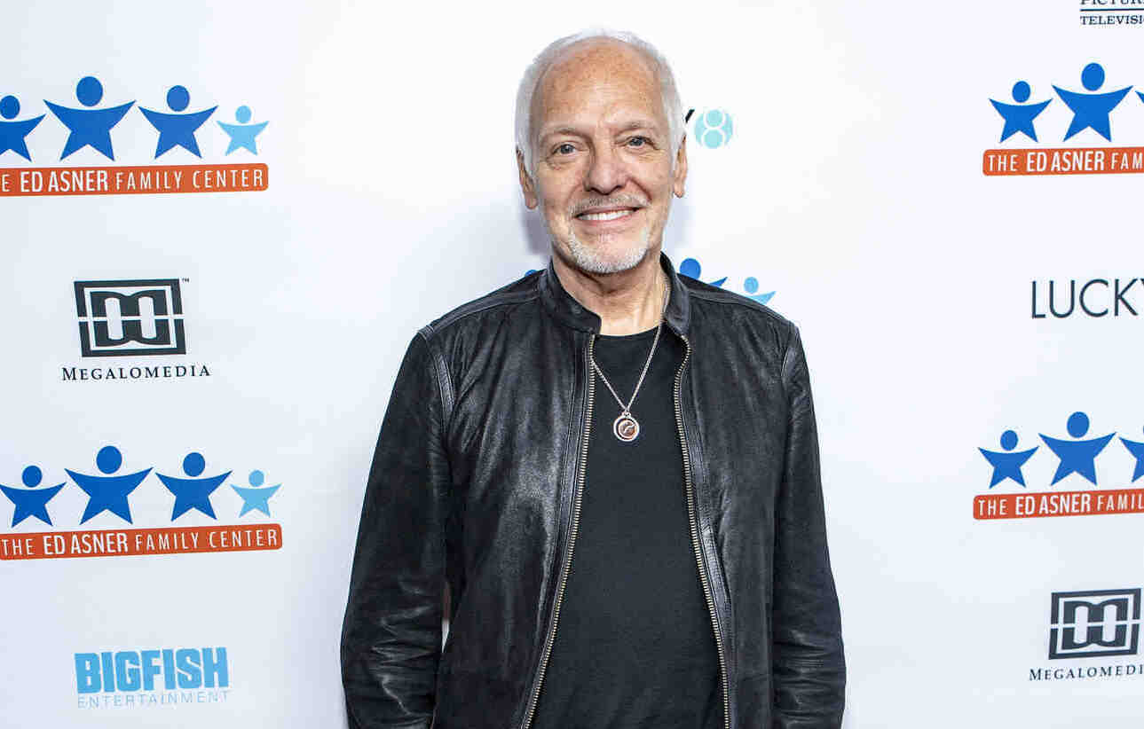Portrait of guitarist and singer Peter Frampton wearing a black leather jacket and a black T-shirt underneath.