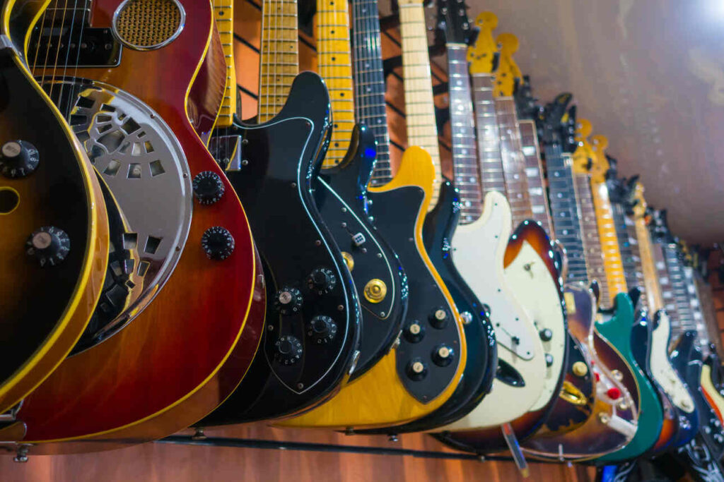 Different kinds of electric guitars hanging on the wall in a guitar shop.