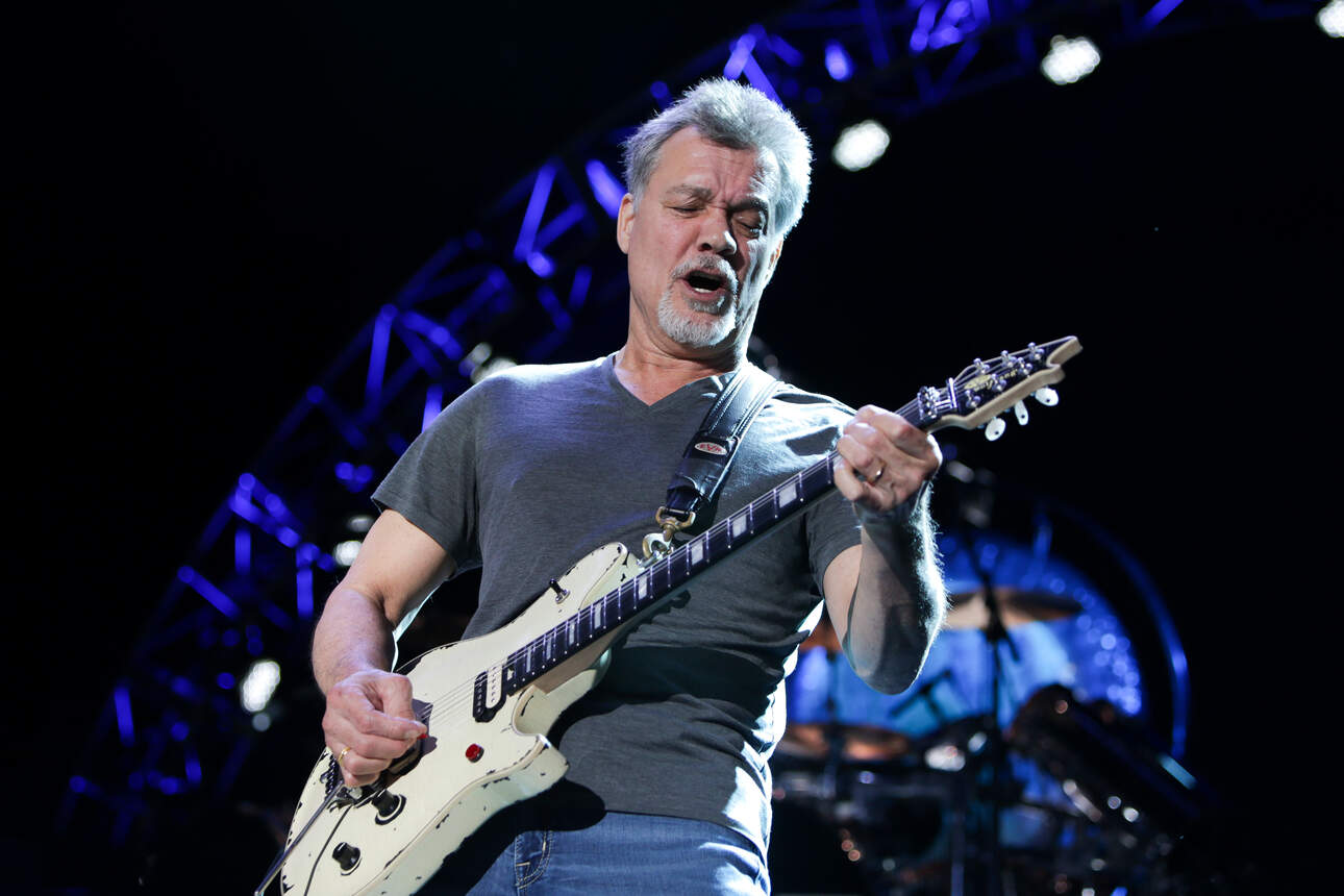 Eddie van Halen on stage playing his white EVH Wolfgang signature guitar.
