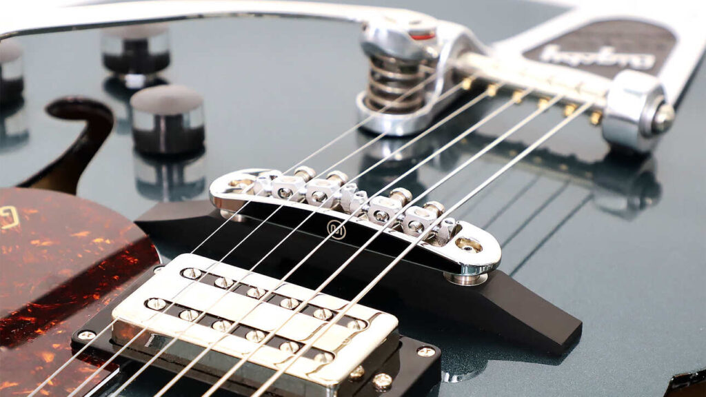 Closeup of a Mastery M10.2 guitar bridge connected to a Bigsby tremelo system on an electric guitar.