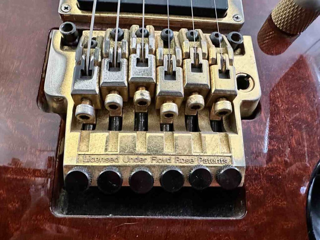 A copper-plated six-string Lo Pro Edge Floyd Rose bridge on an Ibanez S540 electric guitar.