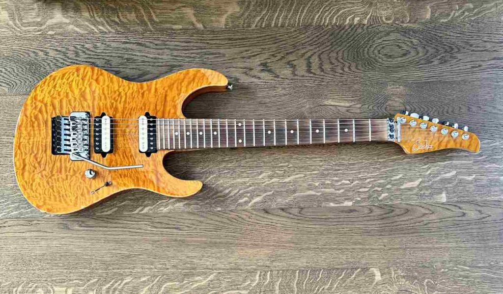 A Suhr Modern custom 7-string electric guitar lying on a black oak table.