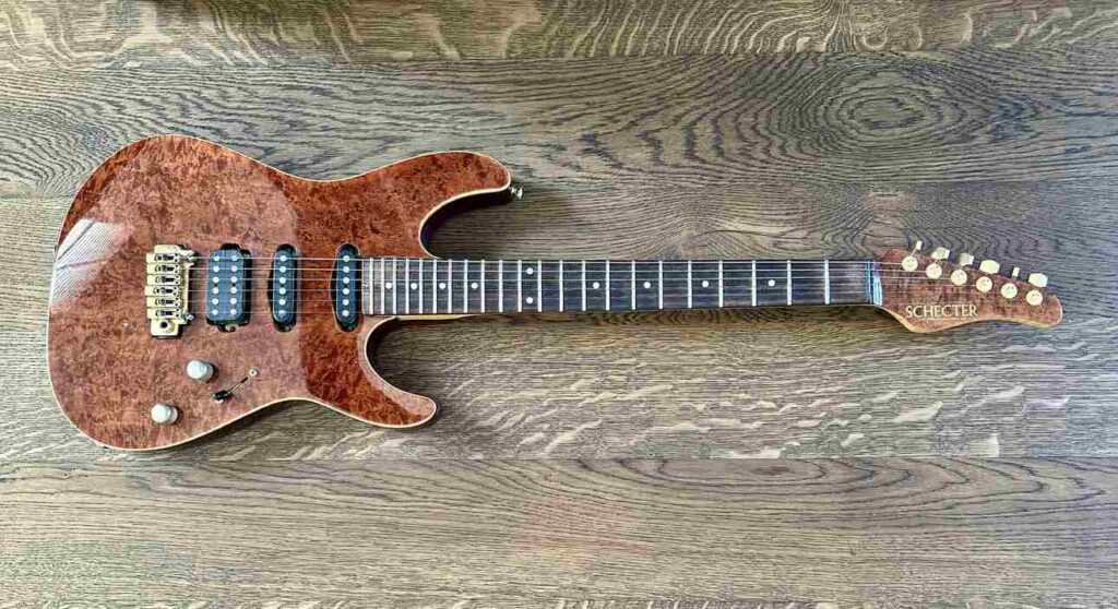 A Schecter Hollywood Custom ltd electric guitar lying on a black oak table.