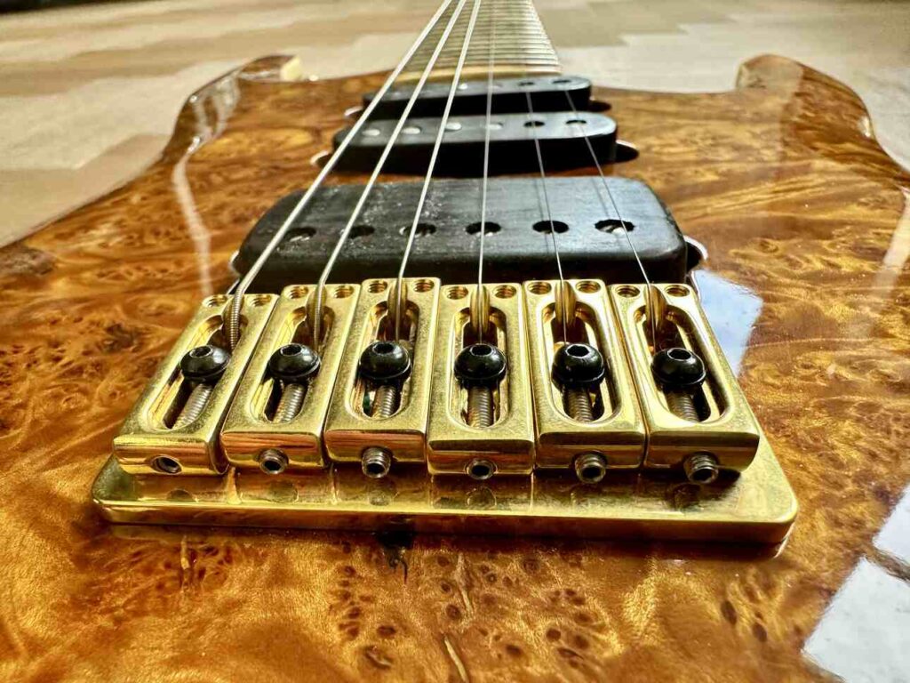 A closeup of a six-string custom-built guitar, seen from behind the bridge.